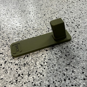 May include: A green plastic gun cleaning mat with a raised section for cleaning a gun barrel. The mat has the word "LOCK" printed on it.