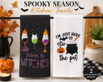 Może przedstawiać: Zestaw dwóch ręczników kuchennych z motywami Halloween. Czarny ręcznik przedstawia trzy kieliszki z płomieniami i napis Bottoms up WITCHES. Biały ręcznik zawiera czarny kociołek, dynię oraz napis I'M JUST HERE TO stir the pot.