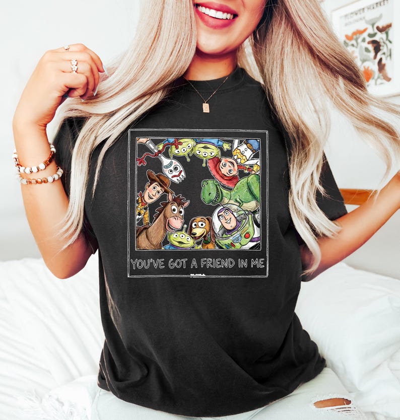 Puede incluir: Camiseta negra con un gr&aacute;fico colorido de personajes de la pel&iacute;cula animada Toy Story. El gr&aacute;fico incluye a Woody, Buzz Lightyear y otros personajes. El texto "YOU'VE GOT A FRIEND IN ME" est&aacute; impreso debajo.