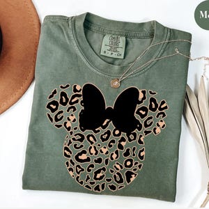 May include: A set of three ceramic mugs with a speckled, matte finish. The mugs are in shades of cream, light brown, and dark brown. Each mug has a simple, minimalist design and a rounded handle.