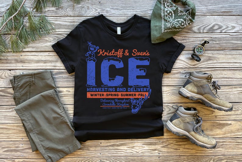 May include: Black t-shirt with the text "Kristoff & Sven's ICE" in blue and orange. The shirt features a graphic of Olaf and Sven. Also pictured are gray pants, hiking boots, a green bandana, and a compass.