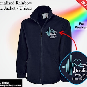May include: A navy blue fleece jacket with a full zip and a high collar. The jacket features a personalized design on the chest, with a heartbeat line, a heart, and the text "Lincoln BSN, RN NeuroICU". The text "Personalised Rainbow Fleece Jacket - Unisex" is at the top.