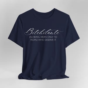 May include: Navy blue t-shirt with the word "Bitchilante" in a cursive font. Below the word is the definition: (N) BEING MEAN ONLY TO PEOPLE WHO DESERVE IT.