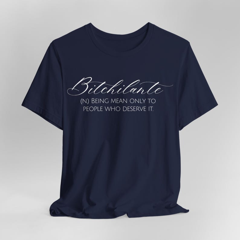 May include: Navy blue t-shirt with the word "Bitchilante" in a cursive font. Below the word is the definition: (N) BEING MEAN ONLY TO PEOPLE WHO DESERVE IT.