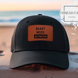 Peut inclure: Casquette de baseball noire avec un patch en cuir marron qui dit "BEAST MODE ACTIVATED".