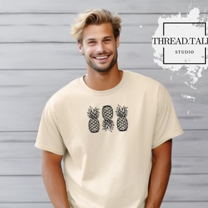 May include: A beige t-shirt with a graphic of three black and white pineapples. The text "THREAD.TALKS STUDIO" is visible in the background.