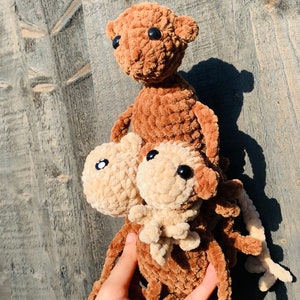 K&ouml;nnte beinhalten: Drei handgefertigte H&auml;kelteddyb&auml;ren in verschiedenen Braun- und Beiget&ouml;nen. Die B&auml;ren haben schwarze Knopfaugen und sind aus einem weichen, strukturierten Garn gefertigt. Die B&auml;ren sind vertikal gestapelt.