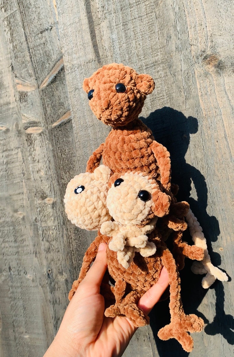 K&ouml;nnte beinhalten: Drei handgefertigte H&auml;kelteddyb&auml;ren in verschiedenen Braun- und Beiget&ouml;nen. Die B&auml;ren haben schwarze Knopfaugen und sind aus einem weichen, strukturierten Garn gefertigt. Die B&auml;ren sind vertikal gestapelt.