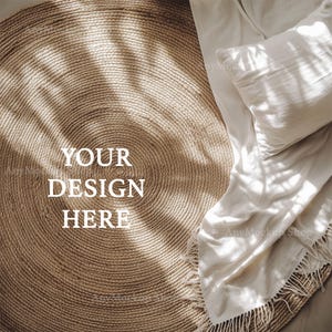 Puede incluir: Una alfombra redonda de fibra natural con textura tejida. La alfombra es de color marrón claro y está hecha de fibras naturales. La alfombra está colocada sobre una manta blanca con una almohada. El texto "YOUR DESIGN HERE" está escrito en la alfombra.