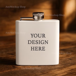 Puede incluir: Una petaca de metal blanco con una tapa plateada y una inscripción negra que dice "YOUR DESIGN HERE" sobre una superficie de madera.