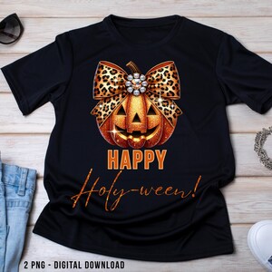 May include: Black t-shirt featuring a Halloween-themed design. The design includes a smiling orange pumpkin with a leopard print bow and the words "HAPPY Holy-ween!" in orange and gold lettering. The shirt is a digital download.