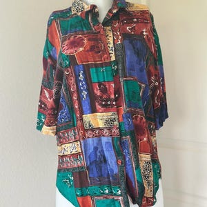 May include: A short-sleeved button-down shirt with a patchwork design. The shirt features a variety of colors, including red, green, blue, and yellow. The pattern includes floral and geometric shapes. The shirt is displayed on a white mannequin.