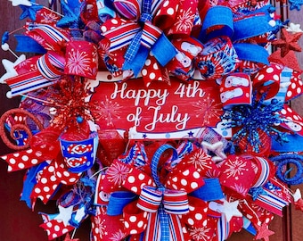 May include: A red, white, and blue Fourth of July wreath with a sign that says "Happy 4th of July". The wreath is decorated with ribbons, bows, stars, and fireworks.