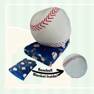 May include: A white baseball-shaped plush toy with red stitching. The toy is open to reveal a blue fleece blanket with a baseball and bat pattern. The text "Baseball Blanket Inside!" is visible on the image.