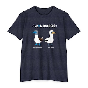Könnte beinhalten: Marineblaues T-Shirt mit dem Schriftzug "i LOVE BOOBIES" und Illustrationen von zwei Blaufußtölpeln. Einer ist ein Blaufußtölpel und der andere ein Nazca-Tölpel. Die Texte "blue-footed booby" und "nazca booby" stehen darunter.