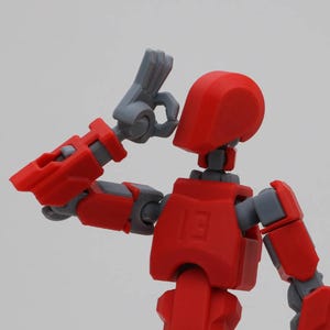May include: A red and gray articulated action figure with a raised arm and hand. The figure has a red head and torso, and gray arms and legs.