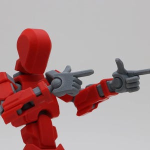 May include: A red and gray articulated action figure with posable arms and legs. The figure is pointing with both hands.