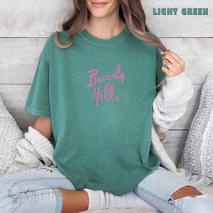 May include: A light green t-shirt with the text "Beverly Hills" in pink lettering.