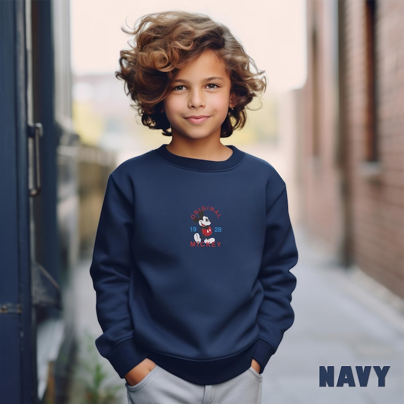 May include: A navy blue long-sleeve sweatshirt featuring a small embroidered graphic of Mickey Mouse in the center of the chest. The graphic includes the text "ORIGINAL" in an arc above, "1928" on the sides, and "MICKEY" below the character.