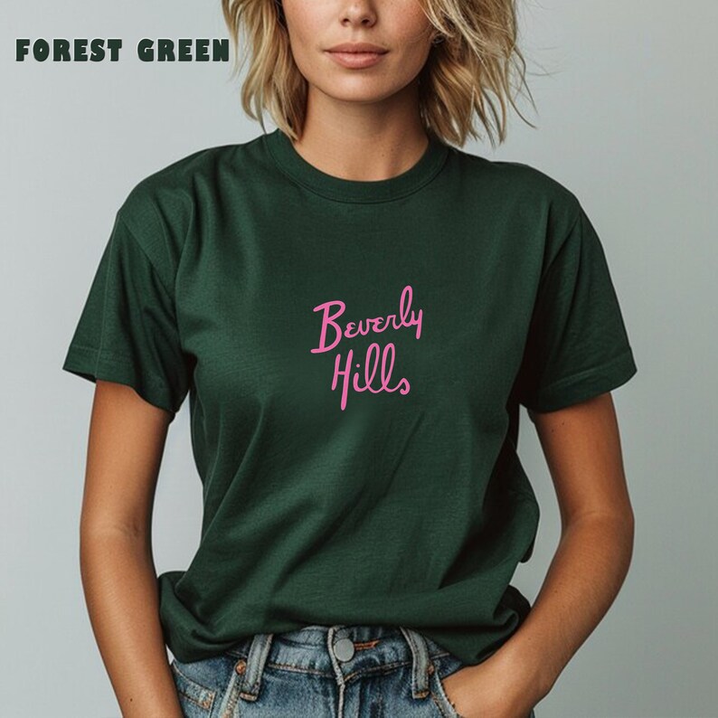 May include: A forest green t-shirt with the words "Beverly Hills" printed in pink on the front.