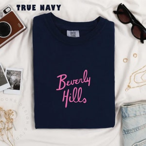 May include: A navy blue t-shirt with the words "Beverly Hills" in pink lettering.
