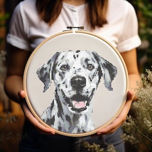Puede incluir: Un primer plano de un aro de bordado de punto de cruz con un perro dálmata blanco y negro con una expresión feliz. La cara del perro es el punto focal de la imagen, con sus manchas negras y su pelaje blanco claramente visibles.