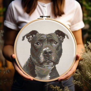 May include: A black and white cross-stitch embroidery of a pit bull dog in a wooden embroidery hoop.