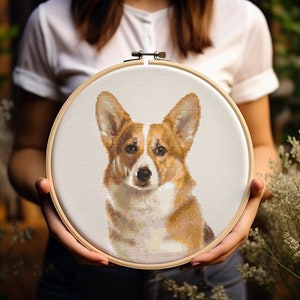 May include: A cross-stitch embroidery hoop with a brown and white corgi dog design.