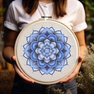 May include: A blue and white mandala cross stitch pattern in a wooden embroidery hoop.