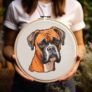Può includere: Un cerchio da ricamo a punto croce con un'immagine dettagliata di un Boxer marrone e bianco. La testa del cane è rivolta verso lo spettatore e i suoi occhi guardano direttamente la telecamera.