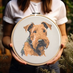 以下が含まれることがあります： 茶色と白の犬の肖像画が施されたクロスステッチ刺繍のフープ。犬は黒い鼻と黒い首輪をしています。