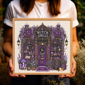 Op de afbeelding: Een vierkant ingelijst kruissteek borduurwerk met een gedetailleerde paarse winkelpui met de tekst WITCH SPELLS boven de deur. Het ontwerp bevat planken met flessen, boeken, hangende lantaarns, paarse bloemen en paddenstoelen in een houten lijst.