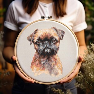 May include: A cross-stitch embroidery hoop with a brown and black Brussels Griffon dog portrait.
