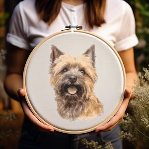 May include: A cross-stitch embroidery hoop with a brown and white Cairn Terrier dog with its tongue sticking out.