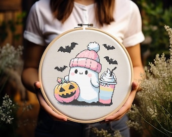 Może przedstawiać: Biały duch w różowo-białym kapeluszu, trzymający różowo-żółtą dynię i różowo-biały milkshake. Duch jest otoczony czarnymi nietoperzami na jasnoszarym tle.