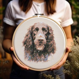 Könnte beinhalten: Ein brauner und weißer Hund mit Schlappohren ist in einem Kreuzstich-Stickrahmen abgebildet. Das Gesicht des Hundes steht im Mittelpunkt des Bildes, mit deutlich sichtbaren Augen, Nase und Maul.