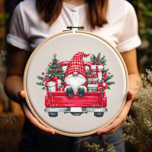 May include: A red truck with a Christmas tree and presents in the back. A gnome is sitting in the truck bed wearing a red hat. The truck is on a white background.