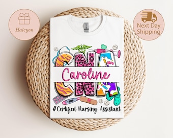 May include: White t-shirt with a colorful design featuring the name "Caroline" and the letters "CNA" in a playful font. The design includes medical-themed graphics and the text "#Certified Nursing Assistant".