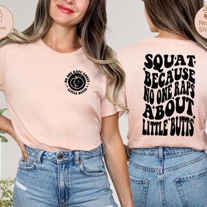 May include: Pink t-shirt with a peach graphic and the text "No one raps about little butts" on the front. The back of the shirt has the text "Squat because no one raps about little butts" in a retro font.