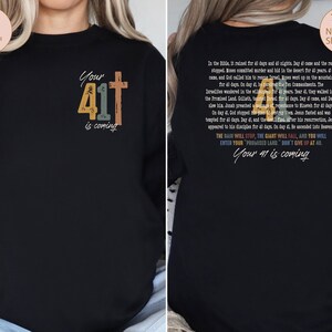 May include: Black sweatshirt with a vintage-style graphic design featuring the number 41 and a cross. The text "Your 41 is coming" is printed on the front of the sweatshirt. The back of the sweatshirt features a longer text about the number 41 in the Bible.