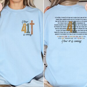 May include: Light blue sweatshirt with a cross and the text "Your 41 is coming" on the front. The back of the sweatshirt has a quote about the number 41 in the Bible.
