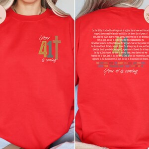 May include: Red long-sleeved sweatshirt with a rainbow-coloured graphic that says "Your 41 is coming" and a cross. The back of the sweatshirt has a text description about the number 40 in the Bible.