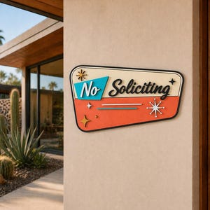 May include: A trapezoidal wall sign with a cream background, a teal section, and an orange section. The sign features the black text No Soliciting in a script font, accented by decorative starburst shapes in white, gold, and black colors.