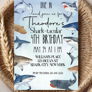 May include: A birthday invitation with a watercolor design featuring various sharks. The invitation reads "Dive In and join us for Theodore's Shark-tacular 4th Birthday" with date, time, and location details. The invitation is set against a light blue background.