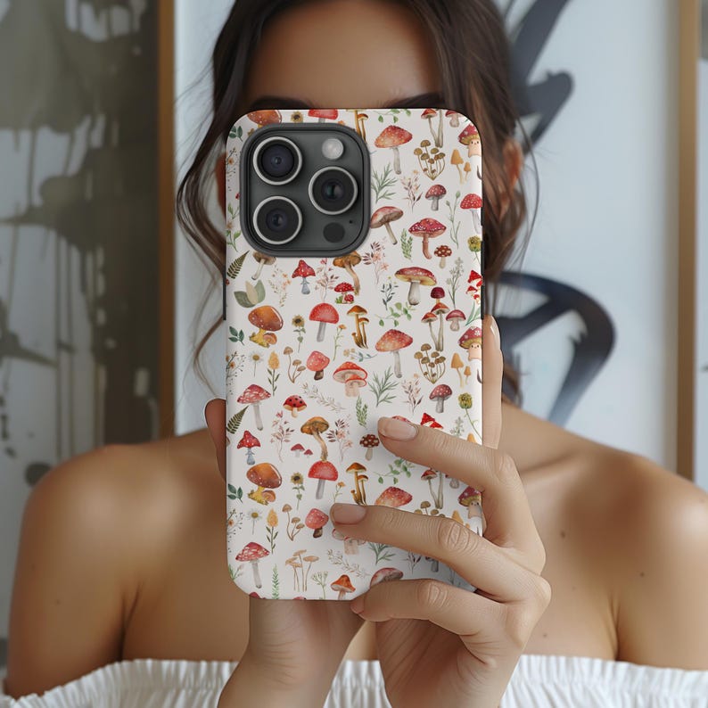 May include: A white iPhone case with a colorful mushroom pattern. The case features a variety of red, orange, and brown mushrooms with green leaves and stems. The case is designed to fit an iPhone 13 Pro Max.