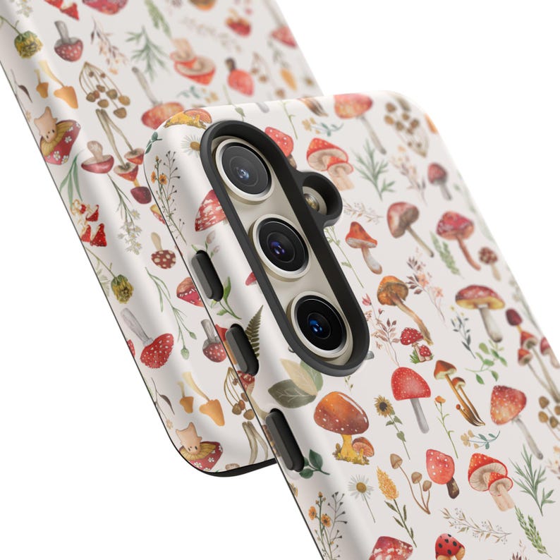May include: A white phone case with a colorful mushroom and floral pattern. The case has a black camera cutout and a raised lip around the edges.