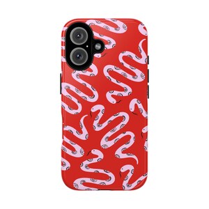 May include: A red phone case with a repeating pattern of pink snakes. The snakes have a curved design with a spiral detail. The phone case has a dual-lens camera and a black frame.