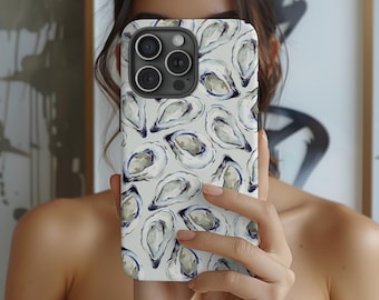 May include: A phone case featuring a repeating pattern of watercolor oysters in shades of white, gray, and blue. The case is held up in front of a person's face, obscuring the face. The phone case has a black camera module.