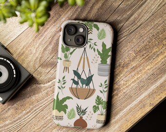 Puede incluir: Una funda de teléfono blanca con un patrón de plantas verdes en macetas y macetas colgantes. La funda del teléfono tiene un recorte para la cámara y un fondo blanco.