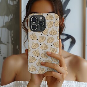 Könnte beinhalten: Eine weiße iPhone-Hülle mit einem Muster aus braunen Khinkali, einer traditionellen georgischen Teigtasche, und schwarzen Punkten.